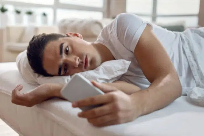 Rapaz sofrendo por amor com o celular na mão