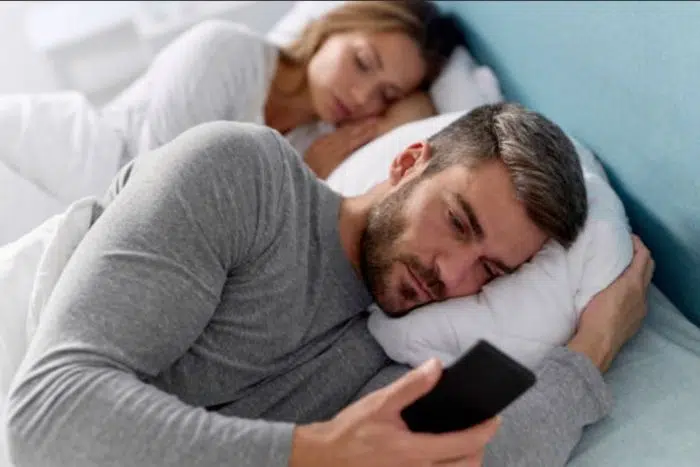 Homem casado com saudade da amante conversando com ela no celular na cama