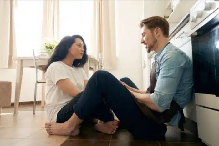 Casal de namorados conversando sentados no chão da cozinha