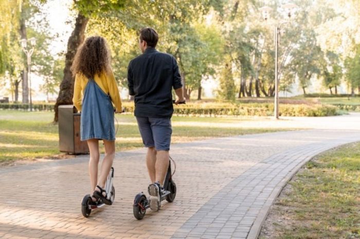 Moça experimentando andar de scooter no parque com o namorado para ser mais interessante para ele