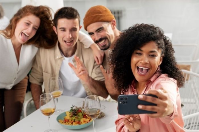 Moça tirando selfie com os amigos para fazer ele mandar mensagem em minutos