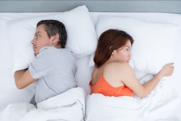 Marido e esposa na cama preocupados porque o marido não procura sexo