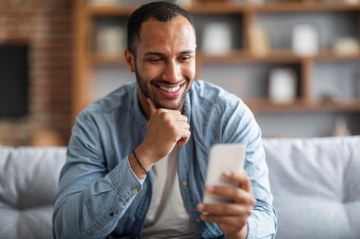 Homem feliz recebendo a mensagem que ele gosta de receber no celular
