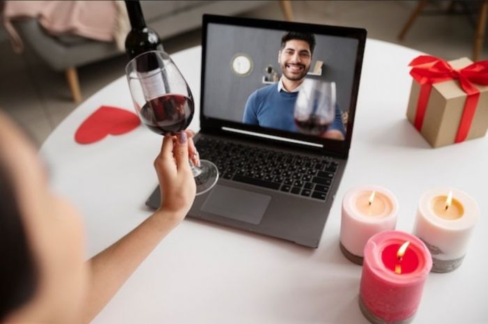 Casal de namorados fazendo vídeo conferência e bebendo vinho
