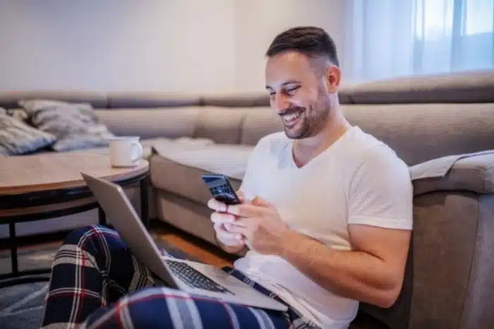 Homem sorrindo olhando para o celular lendo frases de conquista no WhatsApp
