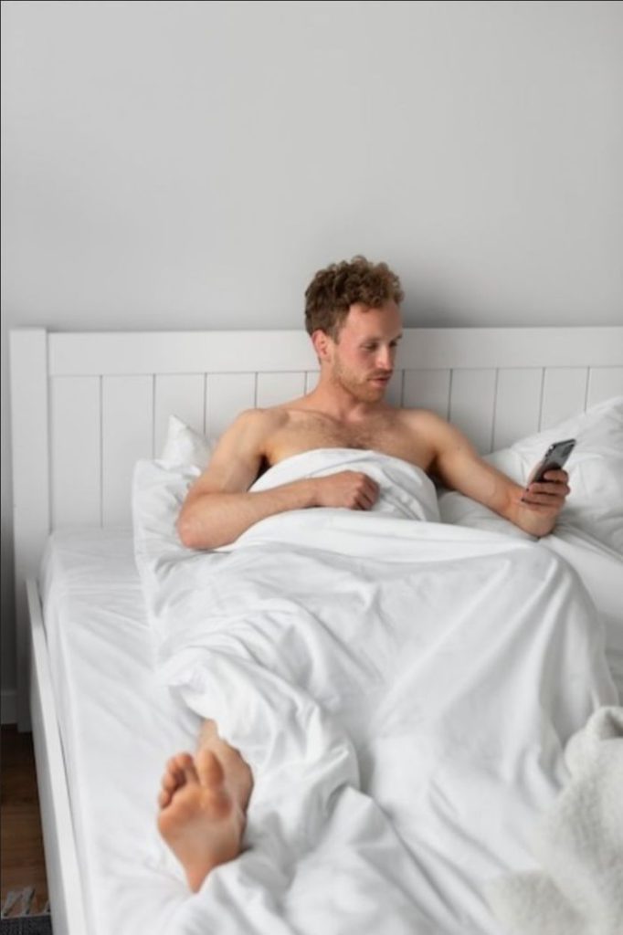 Homem na cama recebendo mensagens sexuais a distância
