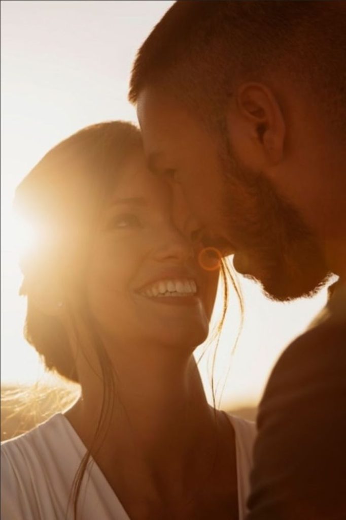 A mulher feliz sorridente ao lado de um homem no pôr do sol
